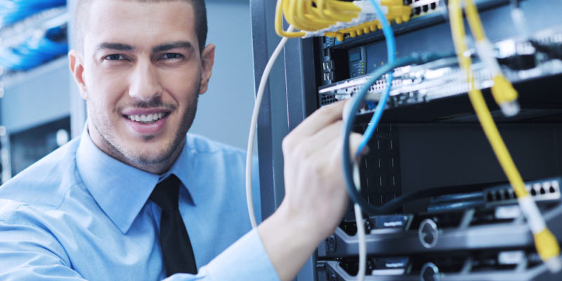 Businessman with laptop in network server room